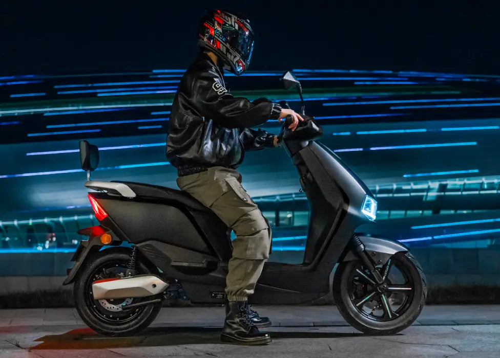 Person sitting on a electic moped with a dark background and blue light effects